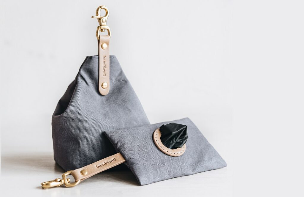 Grey waste bag dispenser and complementary treat bag in waxed canvas cotton and vegetable-tanned leather fittings by Band & Roll.