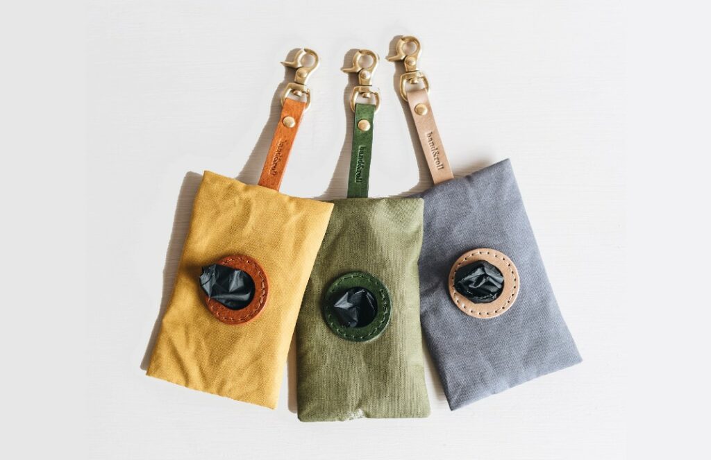 Three waste bag dispensers in mustard, green, and grey by Band & Roll, arranged side by side.