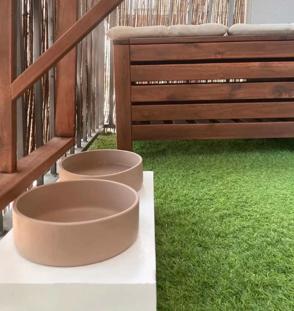 Tadazhi's modern dog bowls placed on a low platform in a small garden